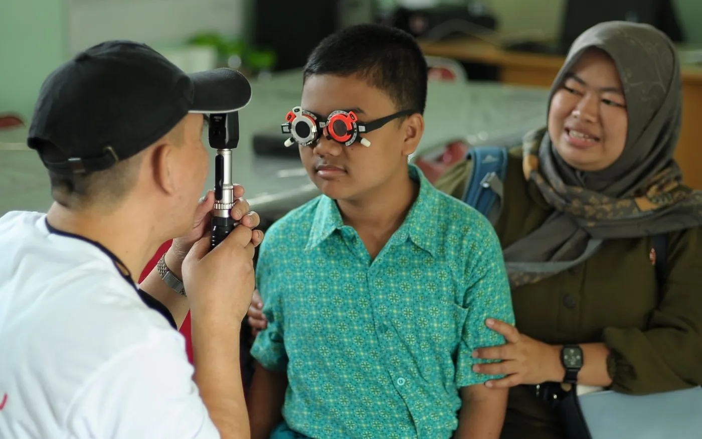 Một bé trai châu Á được kiểm tra mắt cùng người thân