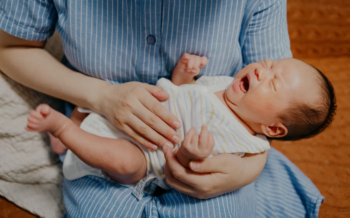 Một người mẹ châu Á ôm em bé sơ sinh tại nhà
