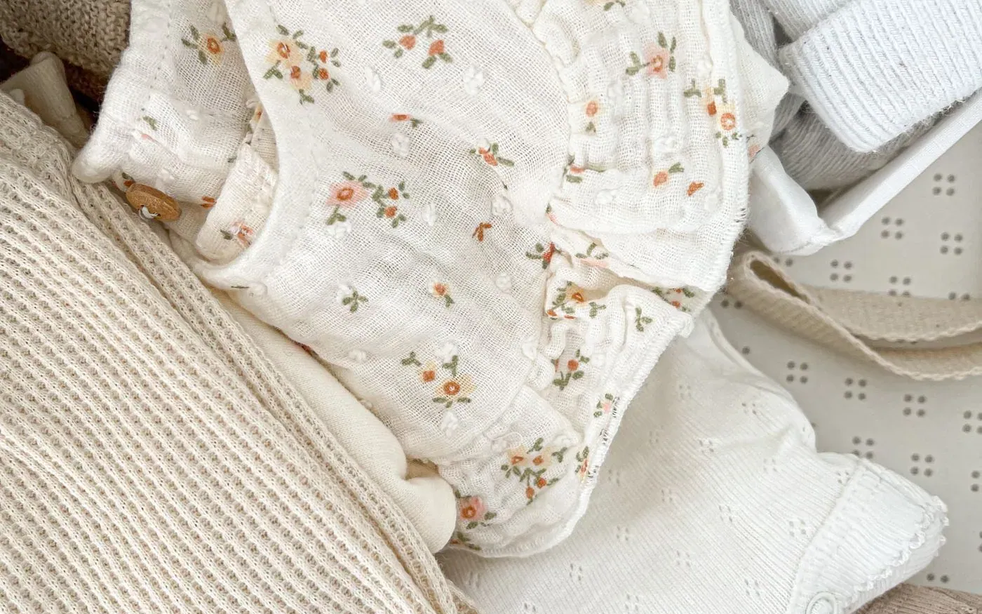 Một ít quần áo em bé màu trung tính được xếp gọn