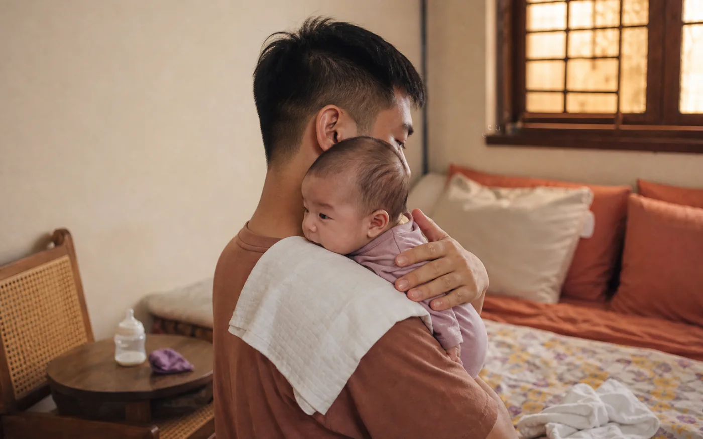 Một người cha Việt Nam bế thẳng em bé trên vai sau cữ bú