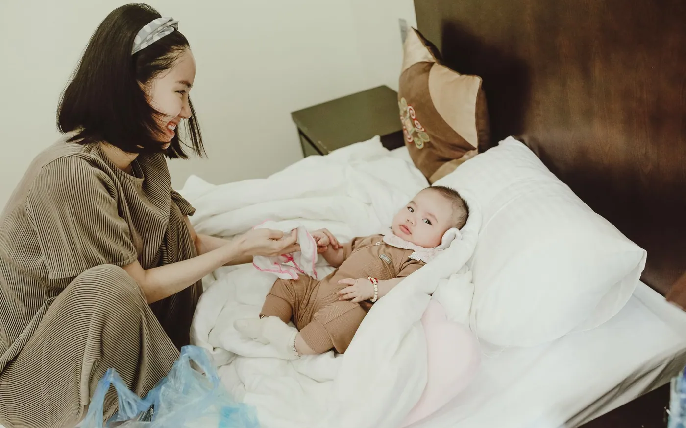 Một người mẹ châu Á nghỉ trên giường cạnh em bé