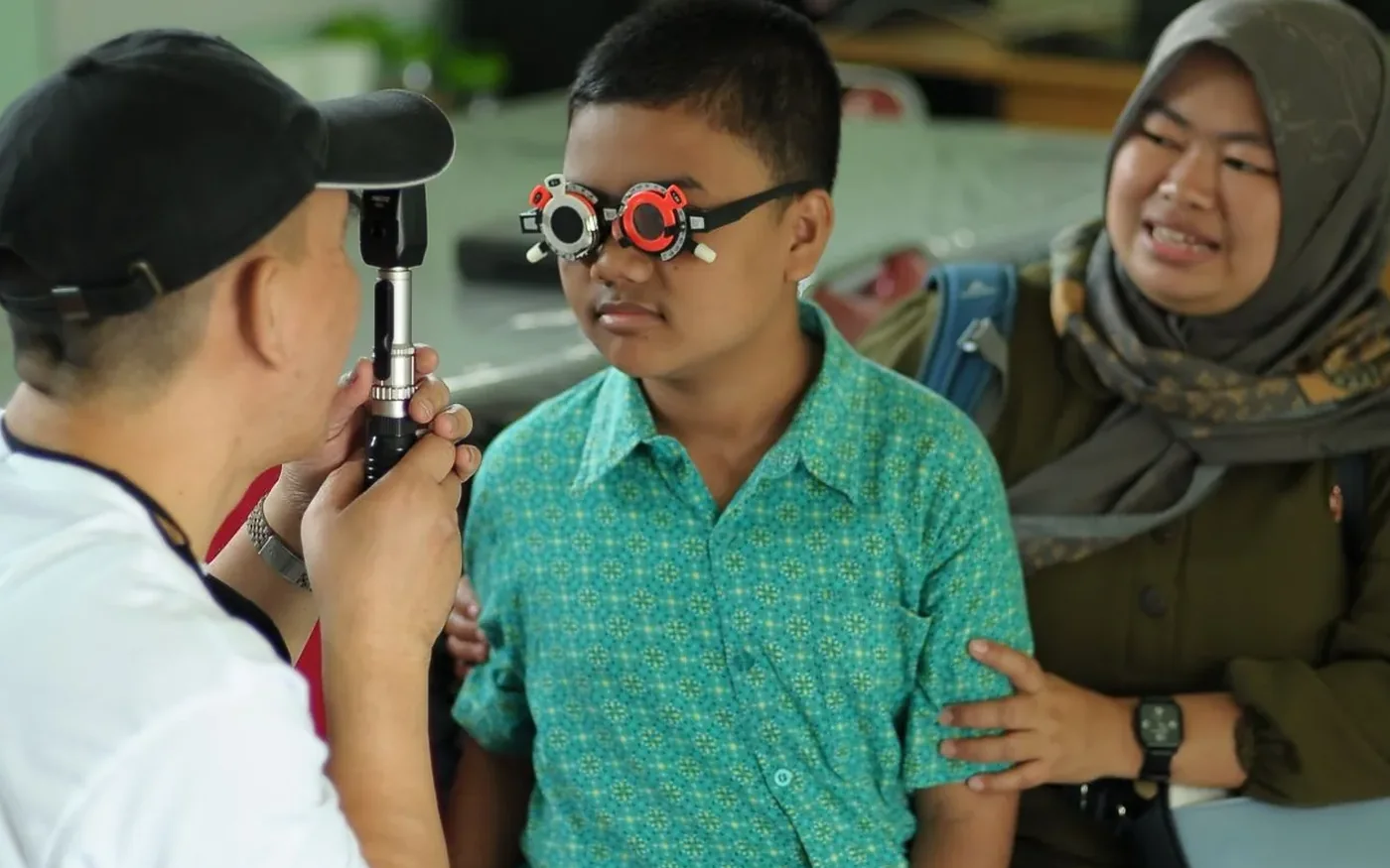 Một bé trai châu Á được kiểm tra mắt cùng người thân