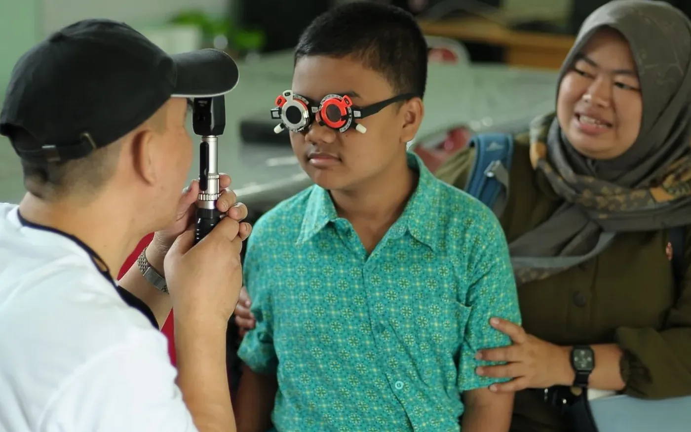 Một bé trai châu Á được kiểm tra mắt cùng người thân
