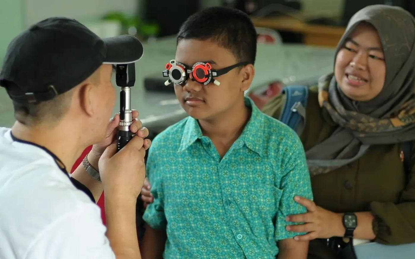Một bé trai châu Á được kiểm tra mắt cùng người thân