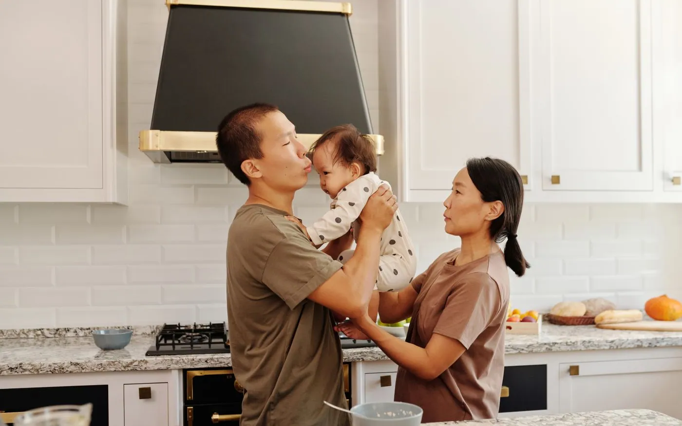Hai người lớn cùng chăm em bé trong bếp