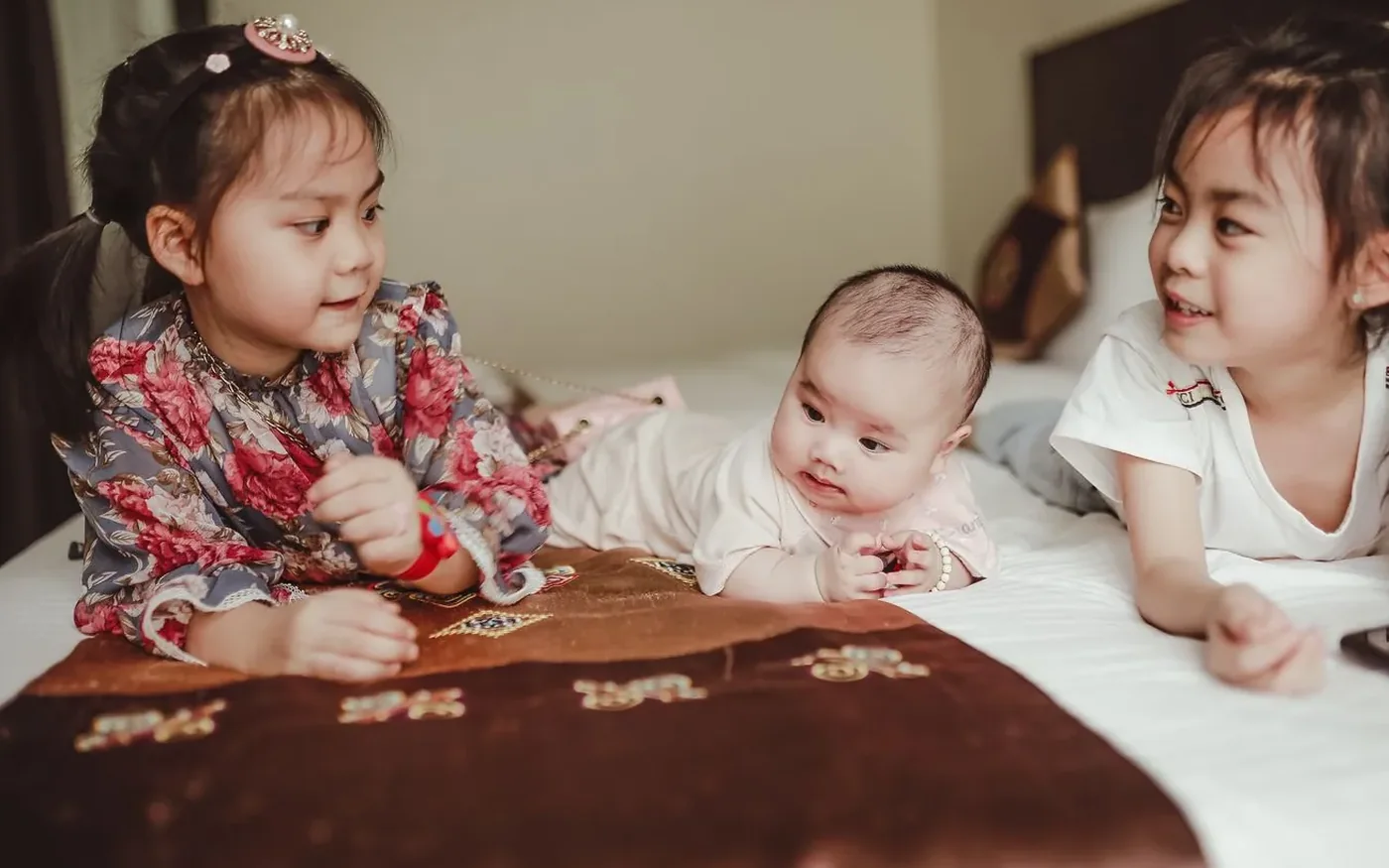 Hai bé gái Việt Nam nằm cạnh một em bé sơ sinh
