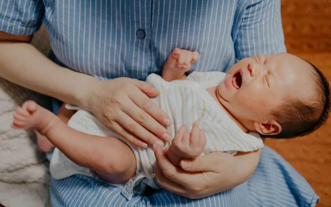Một người mẹ châu Á ôm em bé sơ sinh tại nhà