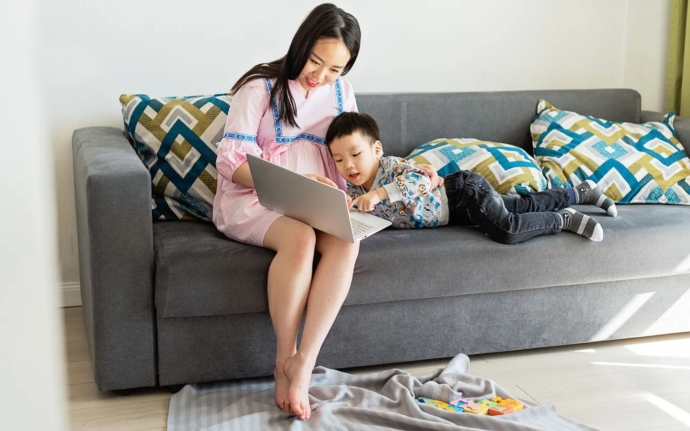 Một thai phụ châu Á dùng máy tính bên con nhỏ