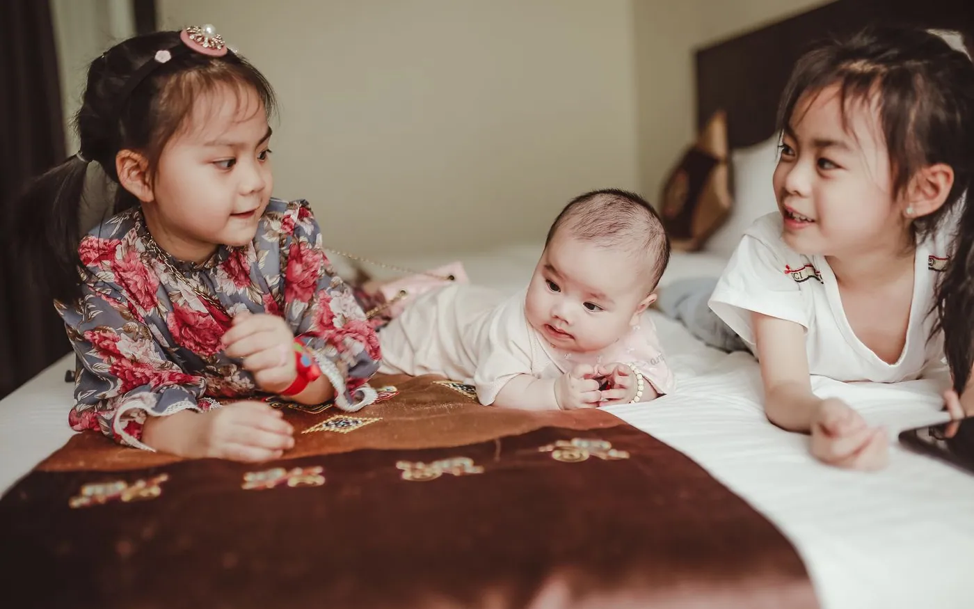 Hai bé gái Việt Nam nằm cạnh một em bé sơ sinh