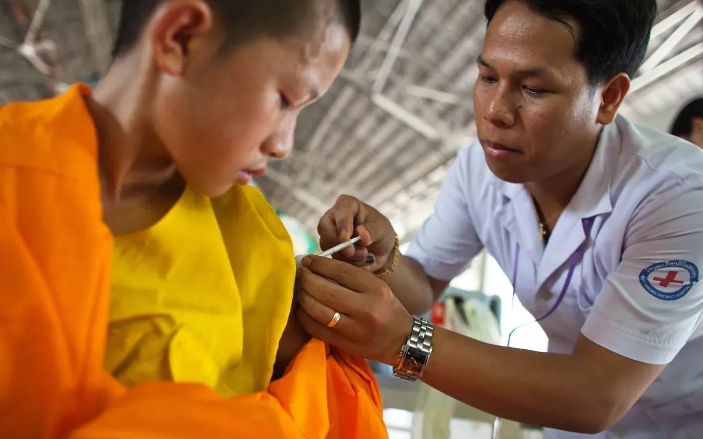 Nhân viên y tế tiêm vắc xin cho một bé trai châu Á